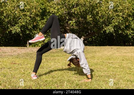 Une fille dans le parc faisant des exercices acrobatiques, jouant à l'extérieur et s'engageant dans des activités de gymnastique. Style de vie sain et sportif Banque D'Images