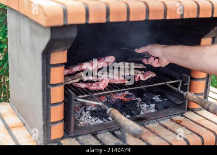 Griller la viande sur un barbecue en briques avec des braises brillantes. Longes de porc, côtelettes et côtes levées sur le gril Banque D'Images