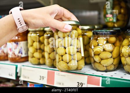 Olives en conserve dans les mains d'un acheteur dans un magasin Banque D'Images