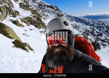 Un alpiniste prenant un selfie sur un terrain enneigé pendant la randonnée Banque D'Images