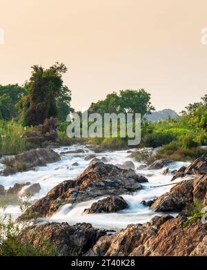 Au Sunset.Sunlight brillant sur les rochers, à côté du mouvement flou de l'eau, se précipitant par, aux principales cascades et rapides de l'île Don Khon. Banque D'Images