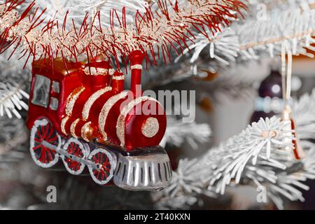 Gros plan du train rouge accroché à l'arbre Cristmas contre les branches blanches Banque D'Images