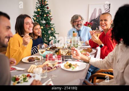 Réunion de famille riante célébrant le repas de Noël ensemble à la table de fête. Les gens s'amusent. Banque D'Images