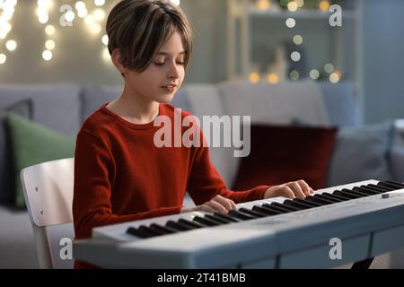 Mignon petit garçon jouant synthétiseur à la maison le soir de Noël Banque D'Images