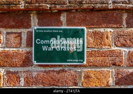 Une plaque verte attachée à un mur de briques rouges à Shaw près de Newbury, Royaume-Uni avec les mots « Commonwealth War graves ». Banque D'Images