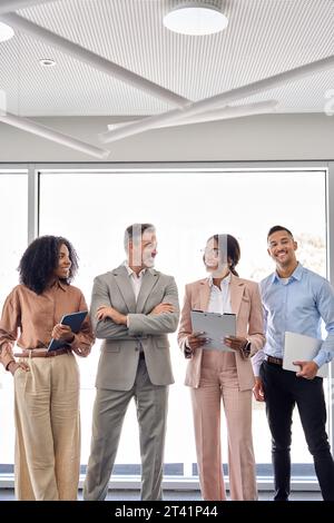 Heureux et divers chefs d'équipe professionnels debout dans le bureau, vertical. Banque D'Images