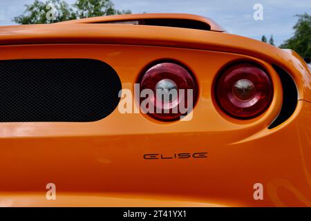 Une vue arrière complète d'une voiture de sport orange avec des feux arrière rouges éclairant la zone Banque D'Images