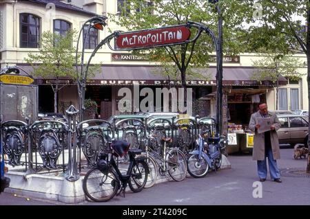 Un homme lit le quotidien dehors à un kiosque de nouvelles près du panneau vintage Metro sur une petite place à Paris, France, Europe Banque D'Images