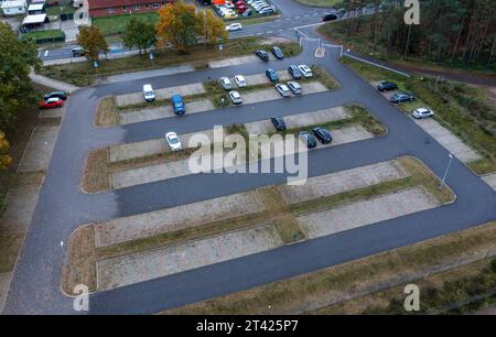 Bandenitz, Allemagne. 27 octobre 2023. Seules quelques voitures sont garées dans un parking pour les navetteurs à la bretelle de Hagenow sur l'autoroute A24 en direction de Hambourg (photo aérienne prise avec un drone). Les habitants du quartier Ludwigslust-Parchim acceptent les trajets les plus longs pour travailler en Allemagne. Selon les calculs de l'Institut fédéral de recherche sur la construction, les affaires urbaines et le développement spatial (BBSR) à Bonn, le trajet moyen aller simple là-bas en 2022 était de 28,6 kilomètres par jour. Crédit : Jens Büttner/dpa/Alamy Live News Banque D'Images