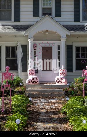 Vue rapprochée d'une porte d'entrée blanche sur une maison blanche de style traditionnel avec de jolies décorations d'Halloween, y compris des jack-o-lanternes roses Banque D'Images