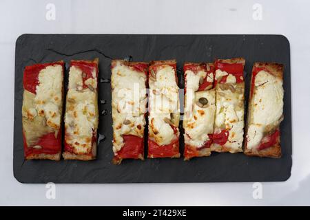 Gros plan d'un assortiment appétissant de pains plats avec diverses garnitures disposées sur une assiette d'ardoise Banque D'Images