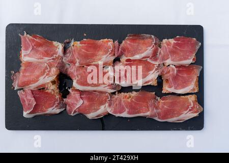 Une planche à découper noire avec de la viande fraîchement tranchée et un petit couteau placé sur le dessus Banque D'Images