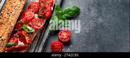 Baguette fraîche avec Caprese. Délicieux sandwich avec tomates et fromage mozzarella avec des feuilles de basilic frais. Conception culinaire italienne. Banque D'Images