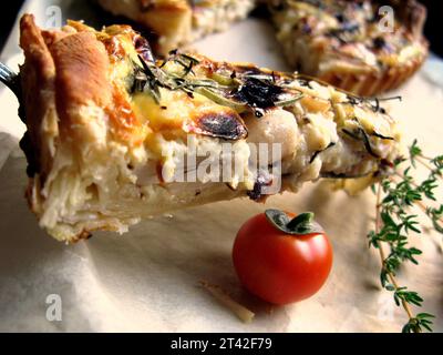 Une image en gros plan d'une tranche de tarte maison avec une tomate sur le côté, maintenue en place par une fourchette Banque D'Images
