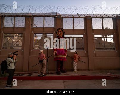 Nogales, Arizona, États-Unis. 27 octobre 2023. Little Amal, la marionnette de 12 pieds d’une réfugiée syrienne, est surmontée par la réalité du mur frontalier séparant la famille et les amis du côté mexicain de la frontière de leurs voisins du côté américain. (Image de crédit : © Sue Dorfman/ZUMA Press Wire) USAGE ÉDITORIAL SEULEMENT! Non destiné à UN USAGE commercial ! Banque D'Images