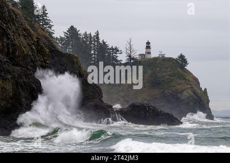 Une scène côtière tranquille avec un phare debout sur un fond de vagues écrasantes sur le rivage rocheux Banque D'Images