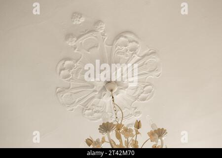 fleurs dans un vase sur une table avec un mur blanc derrière elle et un papillon suspendu au plafond au-dessus Banque D'Images