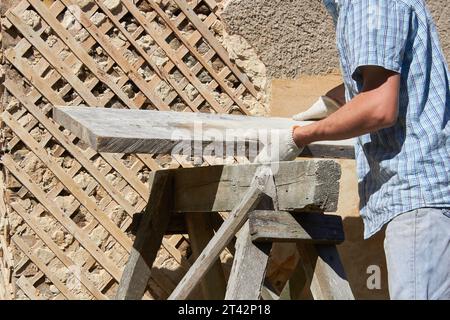 mains du constructeur poser le panneau sur l'échafaudage ancien près du mur de la maison Banque D'Images