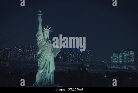 Une image étonnante de l'emblématique Statue de la liberté au centre du cadre, illuminée par une belle toile de fond de lumières nocturnes Banque D'Images