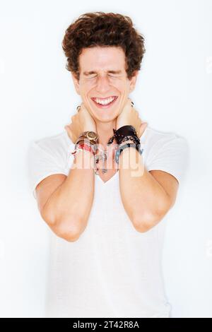 Sourire, mode et un jeune modèle masculin edgy en studio isolé sur fond blanc pour le style rocker. Accessoires, les yeux fermés et un homme punk funky Banque D'Images