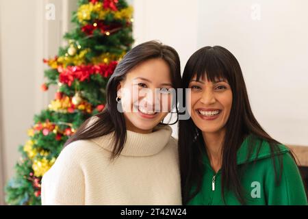 Heureuse mère et fille diverse embrassant dans le salon à la maison, espace de copie Banque D'Images