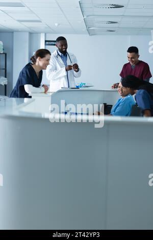 Heureux divers médecins masculins et féminins discutant du travail à la réception à l'hôpital Banque D'Images