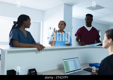 Divers médecins hommes et femmes discutant du travail au bureau de réception à l'hôpital Banque D'Images