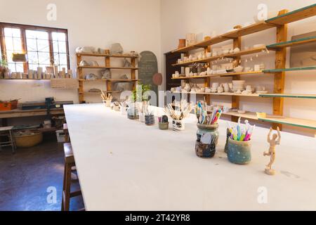 Outils de poterie sur la table et poterie sur les étagères dans l'atelier de poterie Banque D'Images