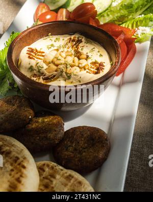 Gros plan d'un plateau de meze avec pain pita, houmous, falafel, olives, tomates, concombre et laitue Banque D'Images