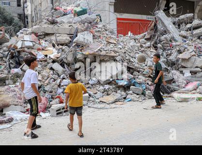 Gaza. 27 octobre 2023. Des enfants palestiniens jouent au football près des ruines dans la ville de Khan Younis, dans le sud de la bande de Gaza, le 27 octobre 2023. Richard Peeperkorn, représentant du territoire palestinien occupé auprès de l'Organisation mondiale de la Santé (OMS), a déclaré vendredi au point de presse que l'OMS avait reçu jusqu'à présent des rapports faisant état de 7 045 décès, dont près de la moitié d'enfants, et de 80 482 blessés, dont 33 pour cent d'enfants. Crédit : Rizek Abdeljawad/Xinhua/Alamy Live News Banque D'Images