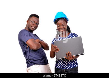 jeune homme debout près de femme ingénieur portant un casque de sécurité bleu avec ordinateur portable tout en souriant. Banque D'Images