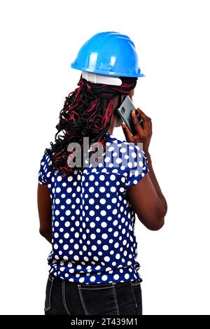 une belle femme ingénieur avec casque de sécurité debout sur fond blanc parlant sur le téléphone portable avec son dos à la caméra. Banque D'Images