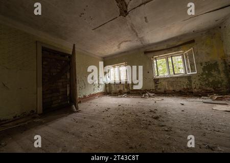 Intérieur de la salle de maison abandonnée minable avec des ordures sale sol en marbre non nettoyé fenêtres brisées porte et murs avec des rayures plafond fissuré Banque D'Images