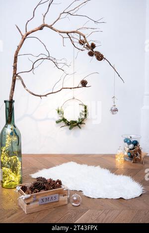 Capturez l'enchantement de la saison des fêtes dans un studio, avec des ornements, des lumières et une branche rustique ornée de pomme de pin. Banque D'Images