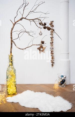 Capturez l'enchantement de la saison des fêtes dans un studio, avec des ornements, des lumières et une branche rustique ornée de pomme de pin. Banque D'Images