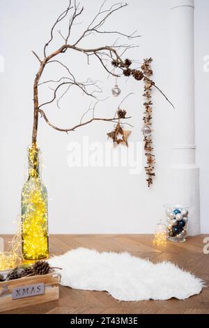 Capturez l'enchantement de la saison des fêtes dans un studio, avec des ornements, des lumières et une branche rustique ornée de pomme de pin. Banque D'Images