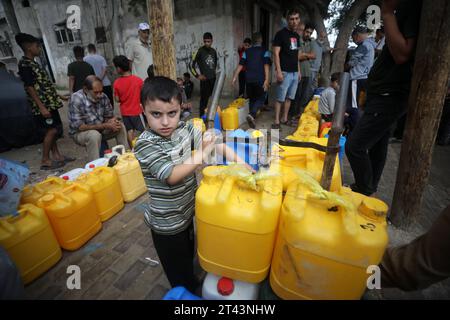 Palestiniens stan prochain jerrycans en plastique à un point de remplissage d'eau, à Rafah, dans le sud de la bande de Gaza le 28 octobre 2023..la grève israélienne se poursuit sur Gaza en raison d'une pénurie de fournitures médicales, d'eau et d'électricité, mais les frappes aériennes israéliennes ont causé des dommages substantiels à l'infrastructure du côté palestinien. Photo par Ismael Mohamad/UPI.. Banque D'Images