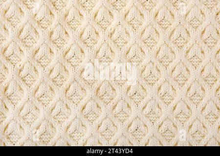 Arrière-plan beige tricoté. Grand tissu tricoté avec un motif. Gros plan d'une couverture tricotée Banque D'Images