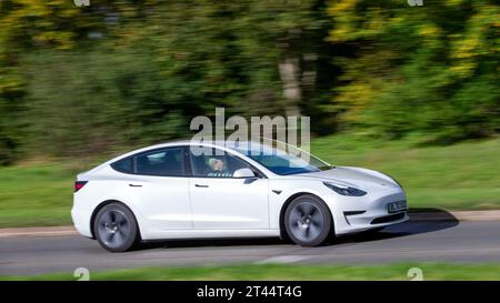 Milton Keynes, Royaume-Uni - Oct 28th 2023:2020 blanc Tesla Model 3 voiture électrique conduisant sur une route anglaise Banque D'Images
