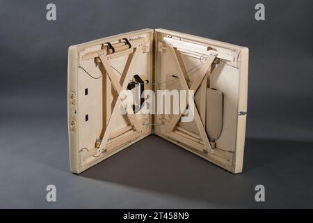 Table de massage pliante portable pour salle de traitement de physiothérapie sur le fond sombre. Banque D'Images