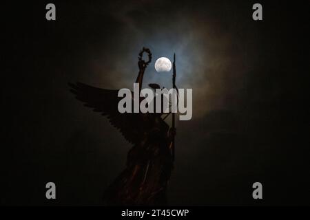 Berlin, Allemagne. 28 octobre 2023. Une éclipse lunaire partielle peut être vue derrière le Gold Else sur la colonne de la victoire. Une éclipse lunaire se produit lorsque l'ombre de la Terre dans l'espace broute la pleine lune. Crédit : Christophe Gateau/dpa/Alamy Live News Banque D'Images