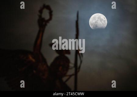 Berlin, Allemagne. 28 octobre 2023. Une éclipse lunaire partielle peut être vue derrière le Gold Else sur la colonne de la victoire. Une éclipse lunaire se produit lorsque l'ombre de la Terre dans l'espace broute la pleine lune. Crédit : Christophe Gateau/dpa/Alamy Live News Banque D'Images