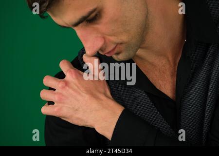 émotions d'un beau gars homme sur un fond vert chromakey gros plan cheveux noirs jeune homme. Personnes, soins de santé et concept de problème Homme malheureux souffrant de douleurs au cou ou à l'épaule à la maison Banque D'Images