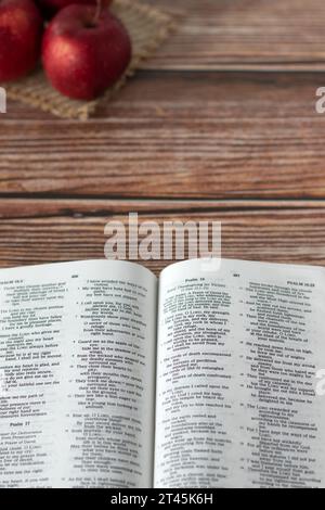 Pommes rouges et livre Holy Bible ouvert sur fond en bois avec espace de copie. Tir vertical. Vue de dessus. Banque D'Images