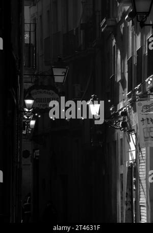 Une ruelle dans le quartier du Raval de Barcelone en noir et blanc avec des lumières et des guirlandes éclairant les bars. Banque D'Images