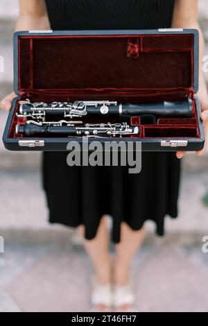 Girl-musicienne tient une clarinette dans un étui dans ses mains. Rogné. Sans visage Banque D'Images