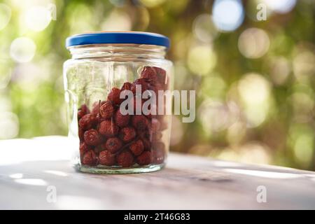 Bocal en verre avec des hanches roses séchées se tient sur une table sur le balcon Banque D'Images