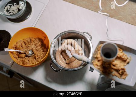 Bol de viande hachée se tient près d'un hachoir à viande électrique faisant des saucisses dans la cuisine Banque D'Images