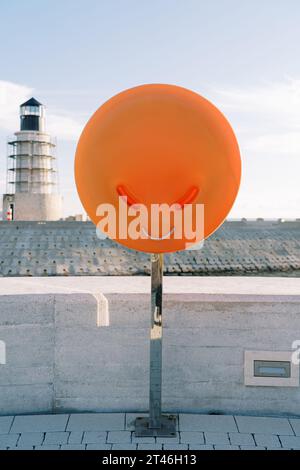 Bouée de sauvetage dans une boîte orange sur la jetée contre le fond du phare Banque D'Images