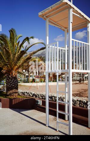 Poteau de garde-côtes en métal se dresse sur la plage près d'un palmier Banque D'Images